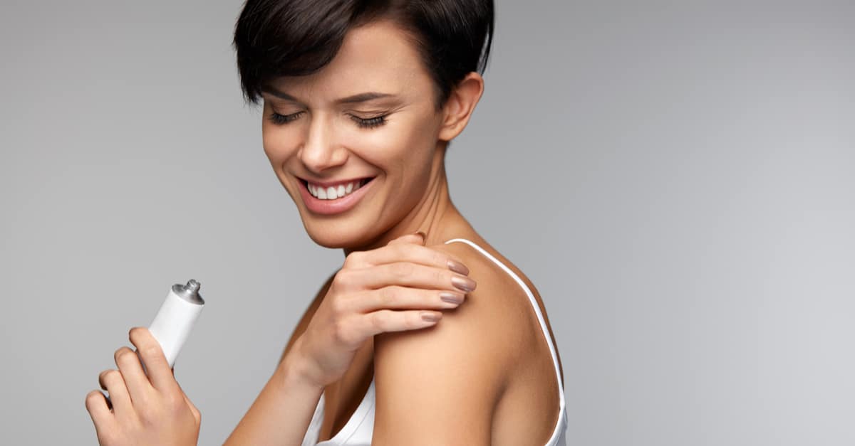 Woman rubs lotion onto shoulder